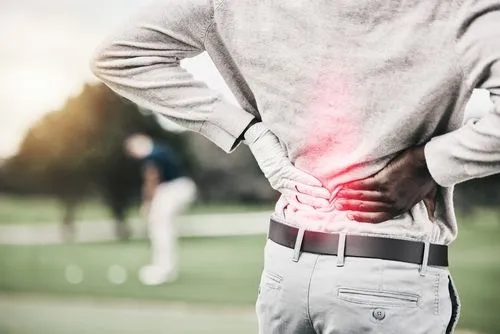 Athlete suffering from back pain while playing golf.