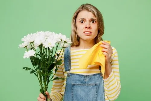 Woman experiencing pollen allergy symptoms against a green background