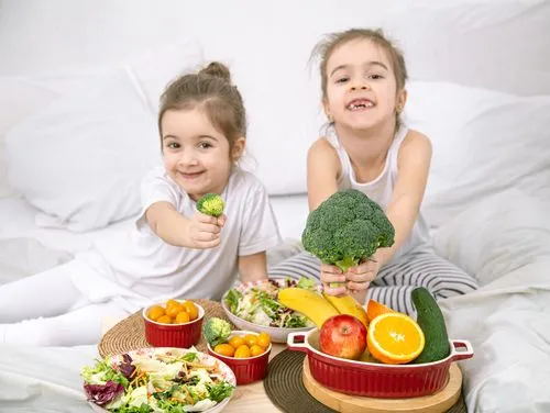 Two children happily eating fruits and vegetables