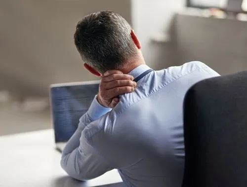 Person on laptop suffering on neck pain in office