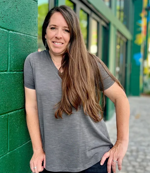 Female standing next to wall smiling