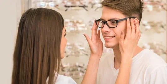 A girl putting eyeglasses to a man