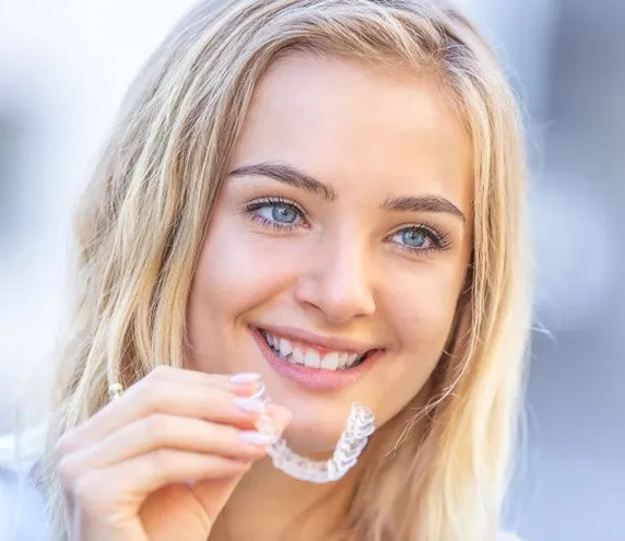 girl smiling holding clear aligner, Invisalign Mt Airy, NC dentist