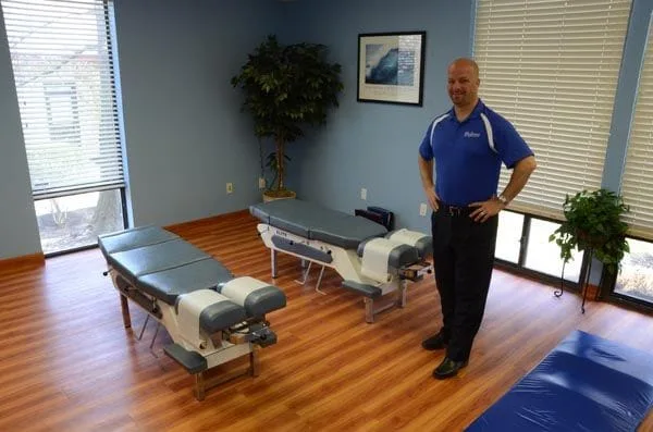 Dr. Madorno standing proudly near two adjustment tables