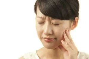 Asian woman wincing in pain and looking for an emergency dentist in Rocky River OH