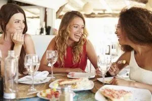 Three friend sit eating lunch smiling with bright healthy teeth from cosmetic dentistry in Rocky River Dentist.