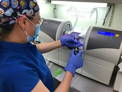 female dental assistant using CEREC machine to mill dental restorations, restorative dentistry Millbrae, CA dentist