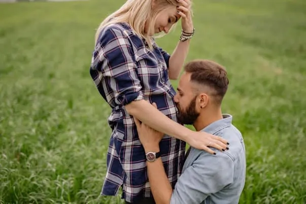 man kissing woman's pregnant belly