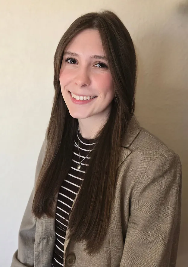 A woman with long brown hair and brown eyes smiles at the camera