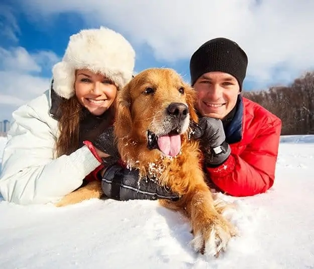Woman and man in the snow with dog