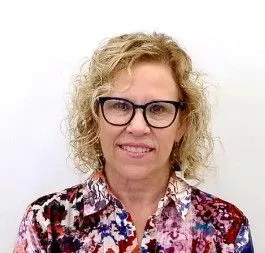 A woman with short curly blonde hair and glasses