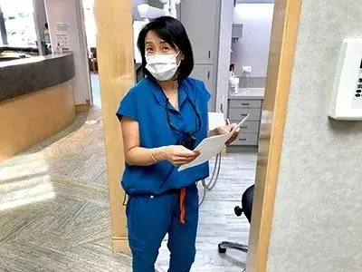 dental staff member holding clipboard in office, dentist Millbrae, CA dental implant restoration