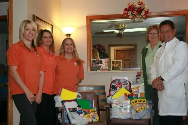 Group photo of employyes with schools supplies that they donated to the C.O.P.E. House for local kids.