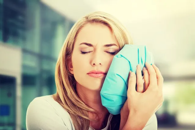 blond woman in pain with ice pack to face, toothache Hazel Park, MI