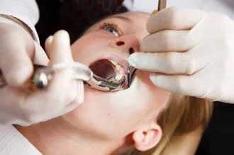 dentist's gloved hands using dental tool to extract a tooth out of a young girl's mouth, tooth extractions Lincoln, NE dentist