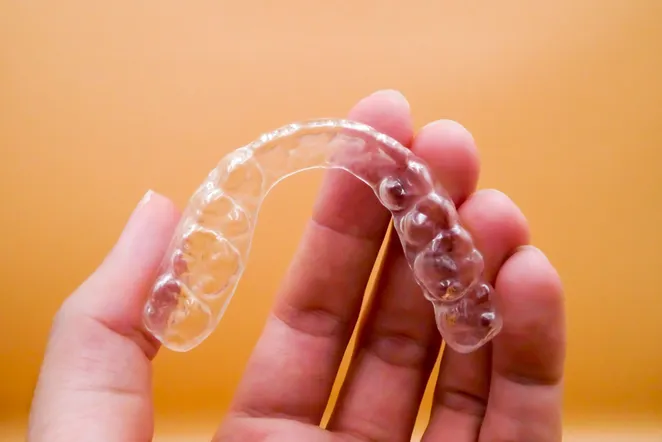 hand holding clear aligner tray, Invisalign Hayward, CA dentist