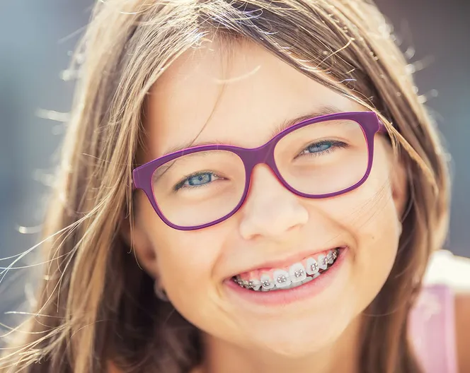 young girl with purple glasses smiling, has braces on teeth, orthodontics Cockeysville, MD dentist