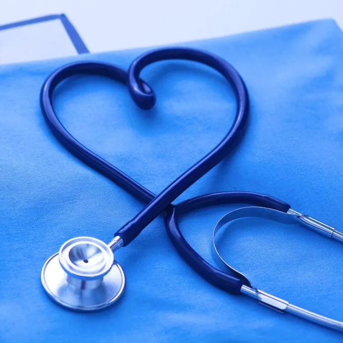 Stethoscope in shape of a heart laid on top of medical scrubs