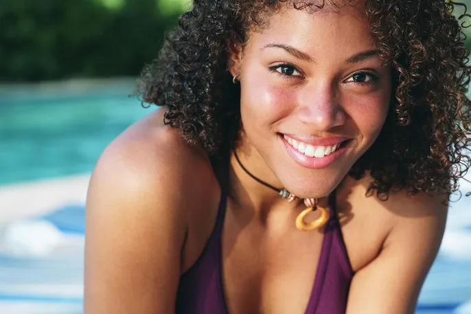 young black woman next to swimming pool, smiling nice teeth, teeth whitening San Diego, CA dentist