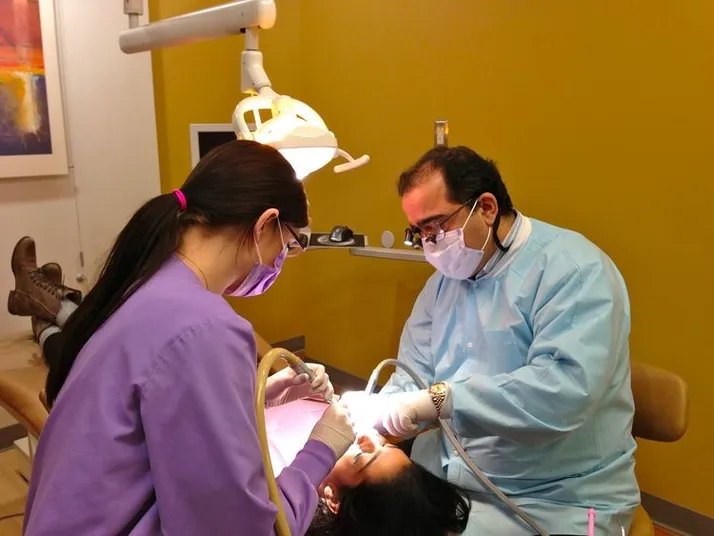 Dr. Samer Dirani, DDS and female assistant performing cosmetic dentistry on patient, cosmetic dentist Novi, MI