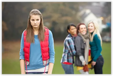 Image of a saddened girl with gossiping girls in the background