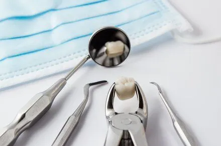 dental tools and extracted tooth on white countertop with surgical mask, family dentistry Windsor Locks, CT dentist