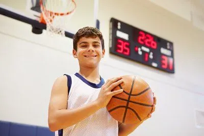 boy on basketball court holding basketball and smiling, athletic mouth guards San Diego, CA dentist 