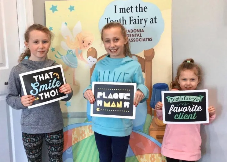 three girls holding up dental themed signs in dentist office, family dentistry Cockeysville, MD dentist