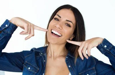 woman smiling pointing at her nice teeth with cosmetic dental veneers Charlotte, NC dentist