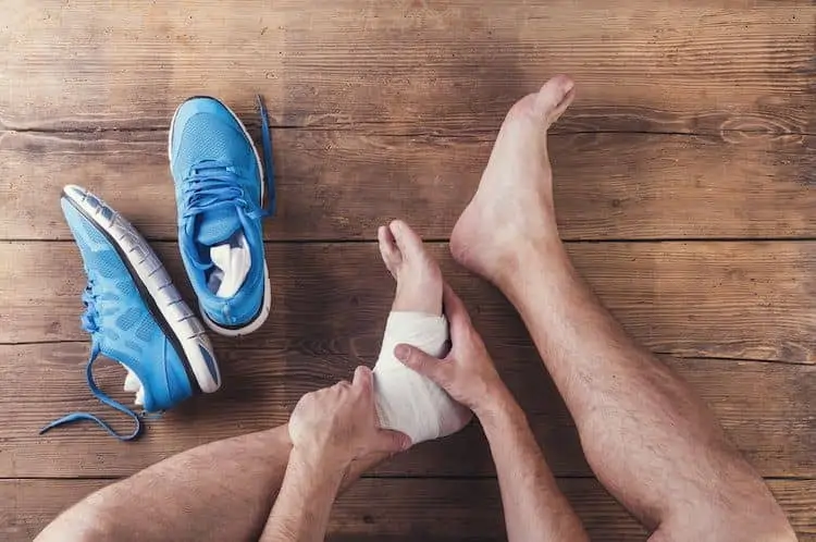 runner holding his foot with sprain bandages after a personal injury