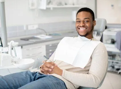 young black man smiling wearing dental bib, sitting in dental exam room, general dentistry Frederick, MD dentist