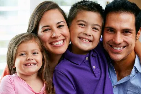 family with mom, dad, and little girl and boy smiling and hugging for group photo, pediatric dentistry Baytown TX