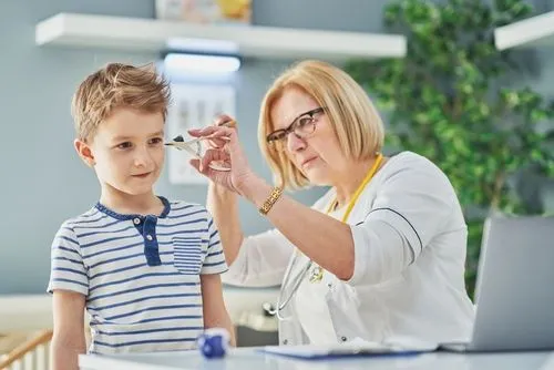 Pediatrician examining a little boy's ear for signs of infection