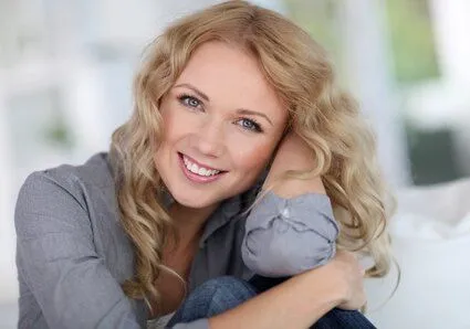 blond woman smiling nice teeth, resting head on forearm, dental crowns Lincoln, NE dentist 