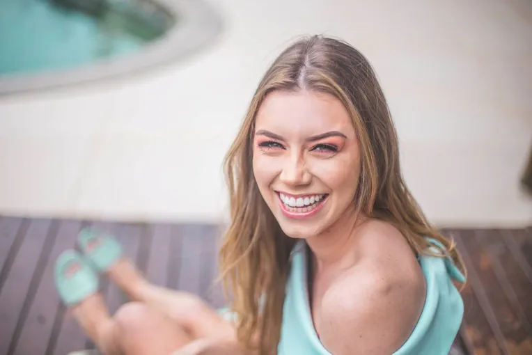 blond woman laughing sitting by swimming pool, nice teeth dental veneers Millbrae, CA