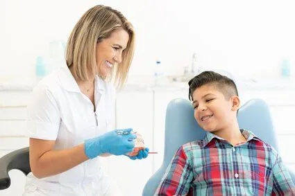 orthodontist showing model of teeth with braces to boy sitting in exam chair, orthodontics Lawrenceville, GA orthodontist