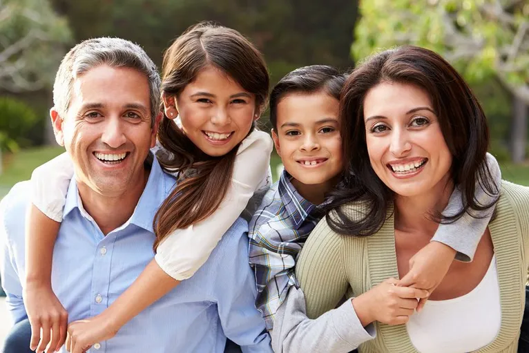 young Hispanic family smiling and posing outdoors, Wallace, NC family dentist