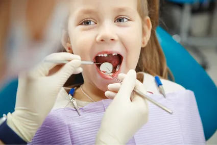 young girl getting dental exam, dentist using tools to look in her mouth, Wauwatosa family dentistry 
