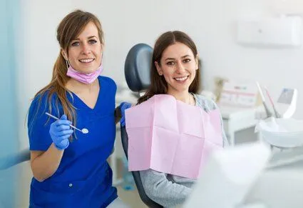 dental hygienist holding dental mirror near female patient in exam chair, dentist Kanata, ON general dentistry
