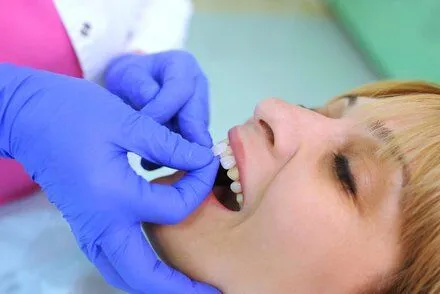 dentist placing porcelain veneer pieces on woman's teeth, veneers Hilo, HI dentist
