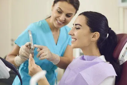 dentist and female patient looking at patient's teeth in handheld mirror, restorative and general dentistry Kanata, ON