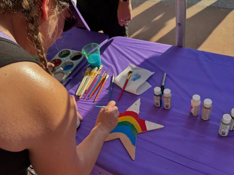 an over the shoulder shot of someone painting a wooden star