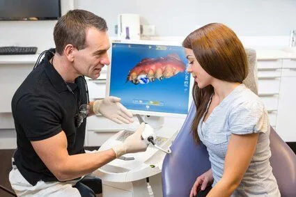 male dentist showing female patient CEREC computer station for same day dental crowns Folsom, CA