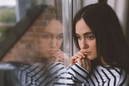 Woman with anxiety and depression looking pensively through window