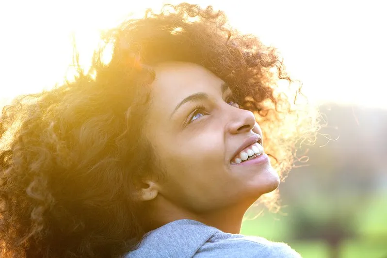 young black woman outside looking up smiling, sun on her hair, General Dentist Frederick, MD