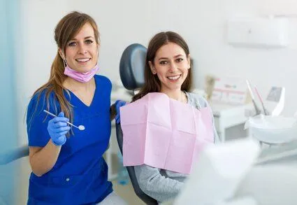 female dental hygienist standing next to young female patient in dental exam room, teeth cleaning Boca Raton dentist