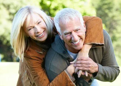 older man and woman outdoors embracing, smiling nice teeth, dentures Lincoln, NE dentist