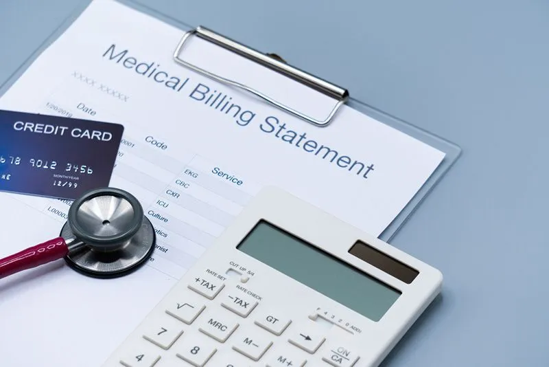 Clipboard with paper titled "Medical Billing Statement" with Stethoscope and Calculator on top