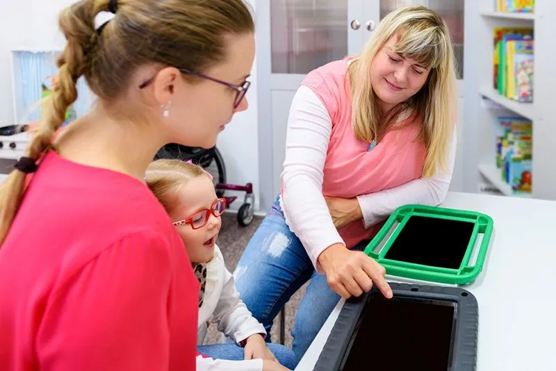 Mother and child being instructed on how to use tablet