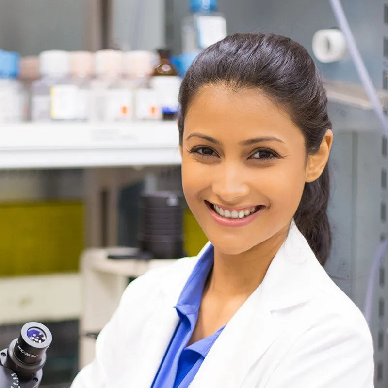 Adult doctor smiling in front of chemicals and lab equipment